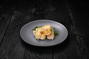 grilled seafood in a gray round plate on a dark wooden table
