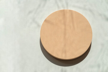 Empty round pastel beige platform podium on white background with natural light and shadows. Mock up background for cosmetic product presentation. Top view