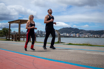 couple running on an athletic track in dark clothes and gymnastics on a sunny afternoon