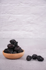 Dates fruits in a wooden bowl on white background, copy space. Organic dried ajwa dates fruits