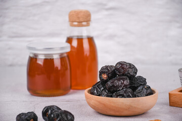 Bowl of dates and jar of honey on a white concrete background. whitespace for your text