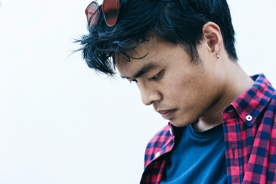 Close Up Of Asian Guy - Asian Young Male Looking Down While Posing For Portrait Against A White Background Outdoors