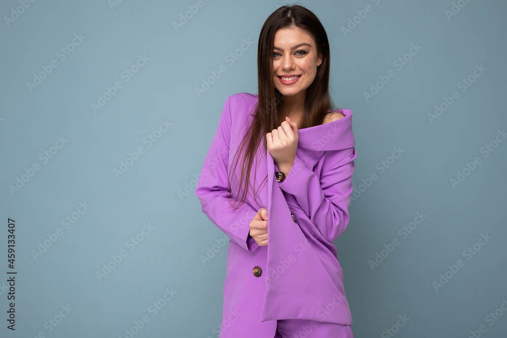 Sticker Photo of positive young business long hair brunette woman wearing purple suit isolated on blue background. Copy space