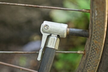 part of the gray pump with a black hose on the nipple of the bicycle wheel