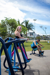 Obraz premium blonde white lady doing physical activity on gym equipment in the park with her friend.
