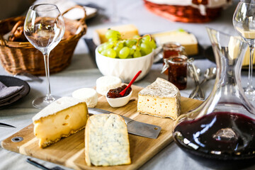 repas de différents fromages accompagné de confiture raisin et vin rouge sur une table - obrazy, fototapety, plakaty