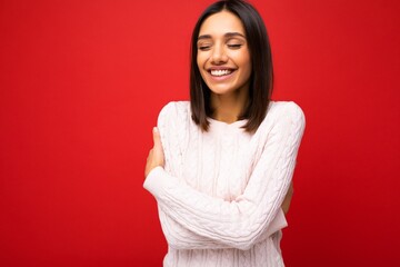 Fototapeta premium Portrait of positive cheerful cute smiling young brunette woman in casual sweater isolated on red background with copy space