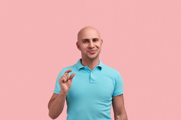 Young bald homosexual man with bristle shows small size with fingers, tells about decreased price,...