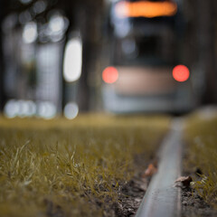 Photographie artistique de rails de tram et d'un tram arrivant en arrière plan flou