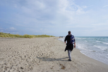 Mann läuft am Strand von Grenen entlang zum nördlichsten Punkt in Dänemark