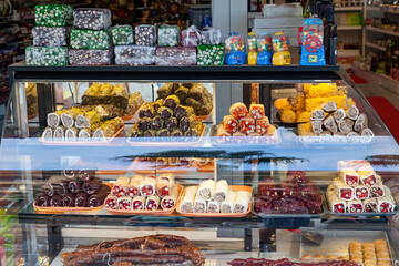 In front of store selling Turkish delight, various locum, arranged like pyramid, with knives, colorful sweets, ready to taste, in Spice bazaar Kemer.