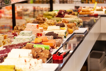 In front of store selling Turkish delight, various locum, arranged like pyramid, with knives, colorful sweets, ready to taste, in Spice bazaar Kemer.