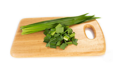 fresh green pandan leaves sliced in wooden chopping board isolated on white background