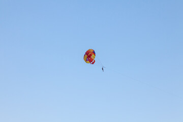 Parasailing water amusement - flying on a parachute behind a boat on a summer holiday by the sea in the resort