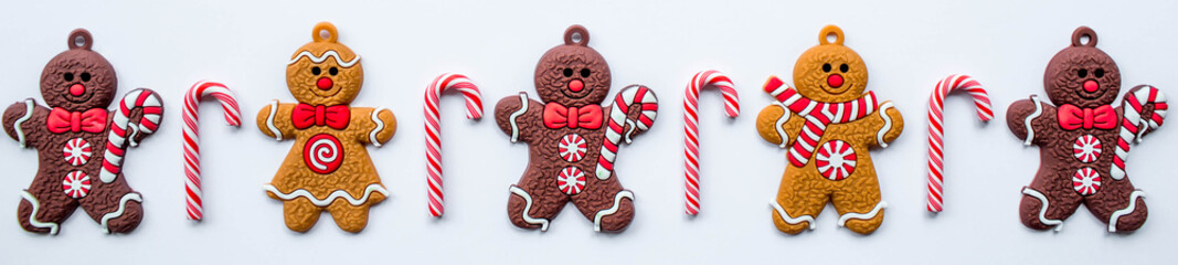 Banner. Gingerbread men and Christmas lollipops on a white isolated background. Cozy concept of New Year and winter holidays. Top view.
