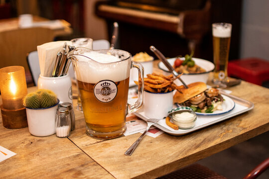 Warsteiner Pils Bier Pitcher im Restaurant mit Burger und BBQ auf Holztisch