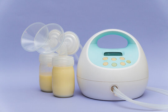 Breast milk pump machine and milk bootles in purple background
