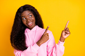 Photo of sweet shite dark skin woman dressed pink hoodie pointing fingers empty space isolated yellow color background