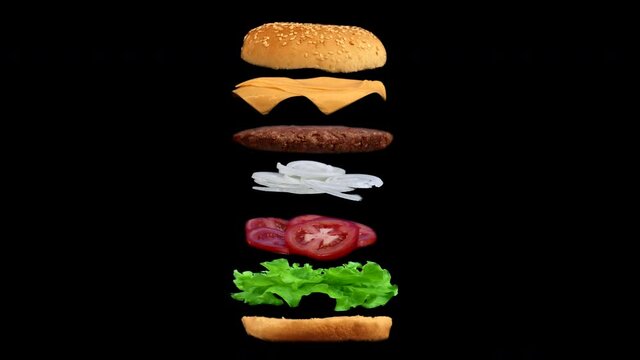 Levitating appetizing burger with flying ingredients on black background. Isolated cheeseburger with meat cutlet rotating. All layers of the dish separately.