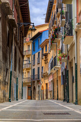Fototapeta na wymiar Colorful house facades and ornate metal balconies with flowers in the old town or Casco Viejo in Pamplona, Spain famous for running of the bulls