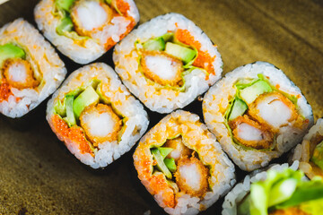 Traditional Japanese rolls with shrimps and vegetables on a plate with wooden chopsticks