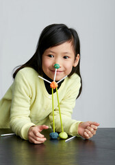 Asian little girl playing with straws and clay indoors