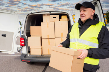 Unloading boxes in cargo van. The postman checks the shipping address. Delivery of parcels. A man...