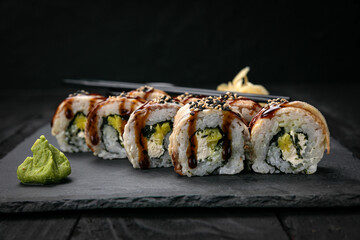 Japanese rolls on a dark plate in a restaurant
