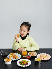 Asian little girl eating and playing indoors by herself