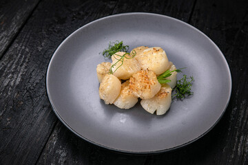 Seafood in a gray plate on a dark wooden table
