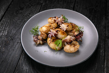 Seafood in a gray plate on a dark wooden table
