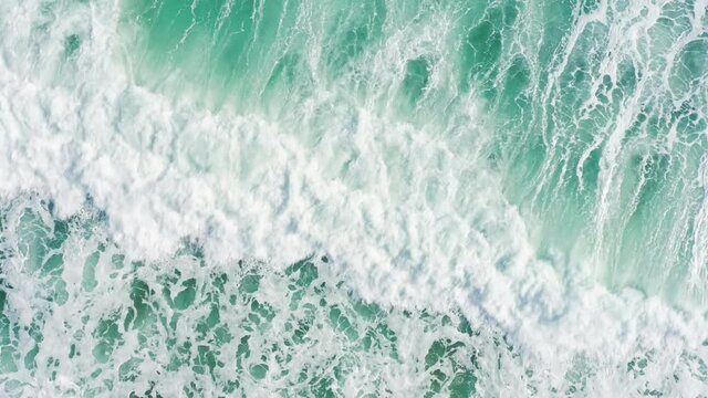 Drone shot of foamy waves covering surfer in Atlantic ocean. Top view of man on surfboard trying to catch a wave in sea. Athletic guy swimming on surfboard. Extreme sports concept, 4k footage