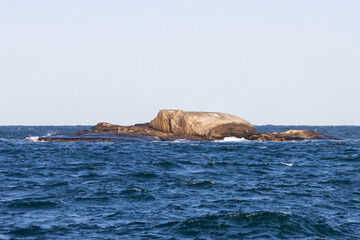Dangerous reef on open ocean. Granite rocks against neutral sky. Shot in Sweden, Scandinavia