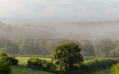 Beautiful early morning autumn landscape with the sun beginning to clear layered mists over a rural valley. Hazy background, with views over the countryside. Selective focus. Hampshire. England. - 459150651
