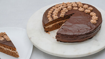 Slice of chocolate cake with chocolate cream topped with chocolate ganache