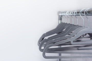 Modern grey empty hangers on neutral wall background.