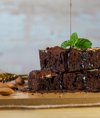 Chocolate spongy brownie cakes with almonds and pouring melted cocoa syrup topping on a stack and...