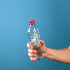 Drink water. The benefits of drinking clean water for the health of the body and well-being. A man's hand hands you a bottle of liquid. Blue background.