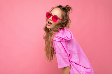 Attractive sexy happy young blonde woman wearing everyday stylish clothes and modern sunglasses isolated on colorful background wall looking at camera