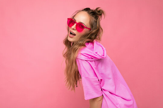 Attractive sexy happy young blonde woman wearing everyday stylish clothes and modern sunglasses isolated on colorful background wall looking at camera