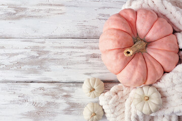 Cozy fall side border on a rustic white wood background. Above view. White blanket, pink and white...