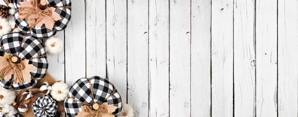 Modern farmhouse fall corner border over a white wood banner background. Black and white buffalo plaid pumpkins and rustic decor. Above view with copy space.