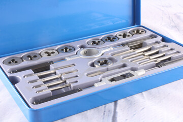 Tap and Die set for threading, repairing and rethreading ISO metric screws. Isolated on pale background with copy space