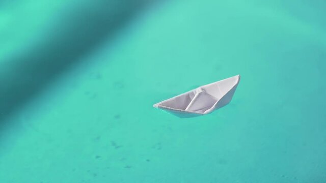 Small paper boat in the water, origami toy that can be used to represent journey, freedom, inspiration or to travel 