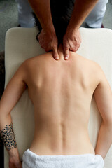 Top view of masseur massaging neck of young woman lying on massage table. Healing body massage at the medical center.