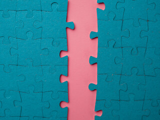 A gap, a crack in the puzzle block. The gap in the team, the division of a large group into two, the concept. Two blocks of assembled puzzles are open with an offset, blue on pink. - obrazy, fototapety, plakaty