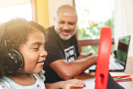 padre y su hija con dispositivos tecnol&oacute;gicos sonriendo en su casa