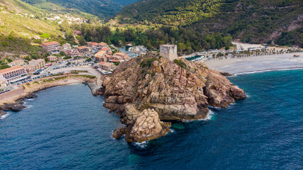 Aerial view of the ruins of the square Genoese tower of Porto at the end of the Gulf of Porto, Corsica, France - Remains of a medieval watchtower overlooking the Mediterranean Sea - obrazy, fototapety, plakaty