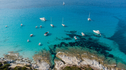 Aerial view of Loto Beach in the Agriates Desert northwest of Saint Florent near the Cap Corse, Corsica, France -Leisure boats moored in azure waters by a rocky shoreline in the Mediterranean Sea - obrazy, fototapety, plakaty