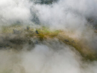 Thin morning fog over a mountain village. Fog covers the Ukrainian slopes of the mountains. Aerial drone view.